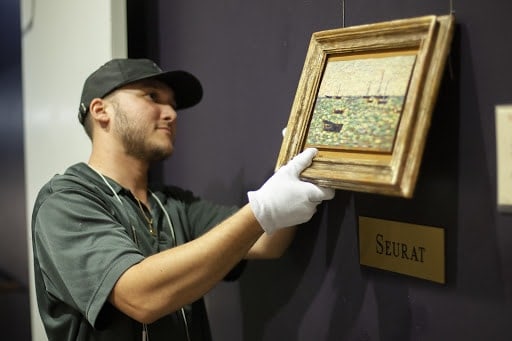 Customer Story: How M.S. Rau Antiques in New Orleans Acquires Affluent Clientele 12 Man with gloves holding painting